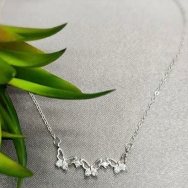 A sterling silver shiny butterfly necklace with cubic zirconia butterfly charms, displayed on a neutral background.