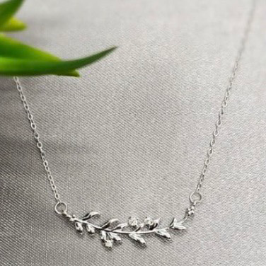A sterling silver necklace featuring a fine detailed leaf design with horizontal bar, displayed on a neutral background.
