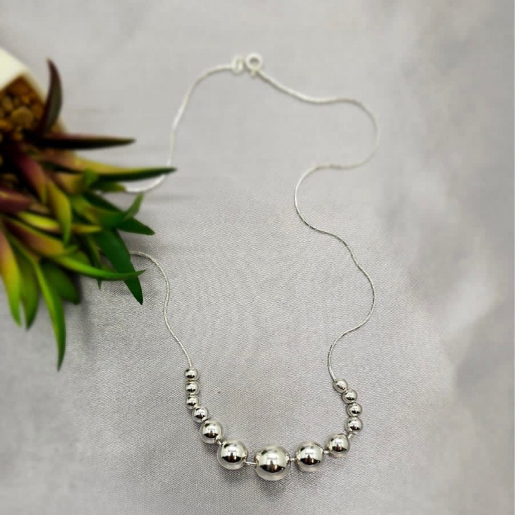 A sterling silver necklace with 13 silver balls, displayed against a white background with a floral accent.