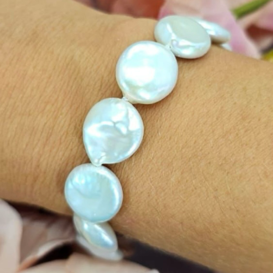 A close-up image of a white coin pearl bracelet with sterling silver, displayed on a person's wrist.