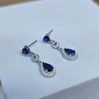 Pair of blue teardrop earrings on a white box