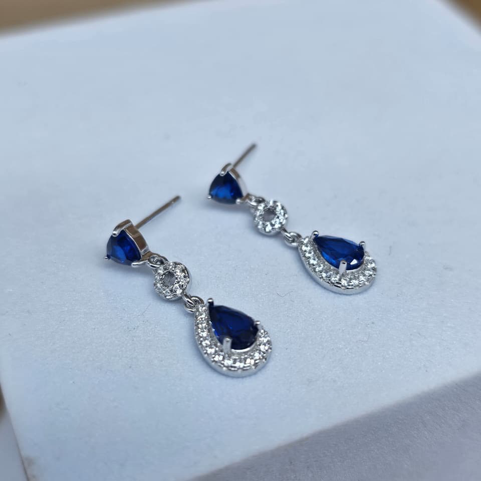Pair of blue teardrop earrings on a white box