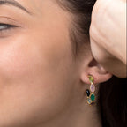 Close-up of a woman wearing colorful earrings with a neutral background
