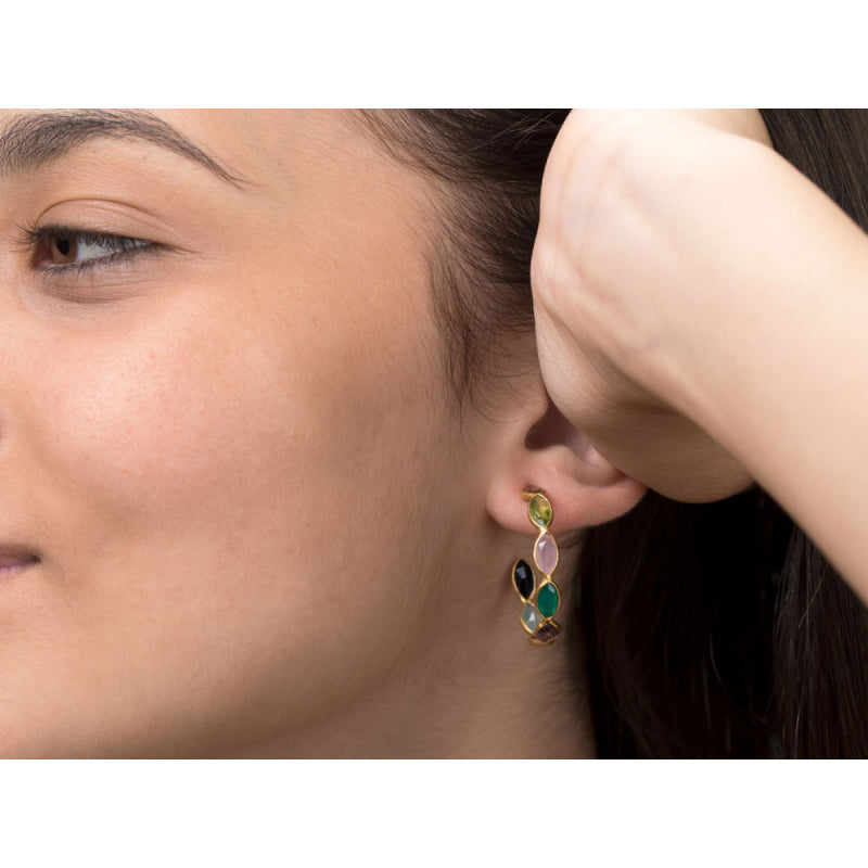Close-up of a woman wearing colorful earrings with a neutral background