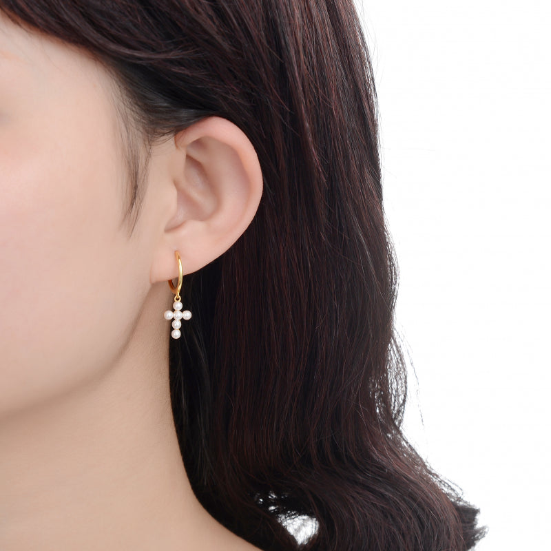 Gold earring with pearls worn by a person on a white background