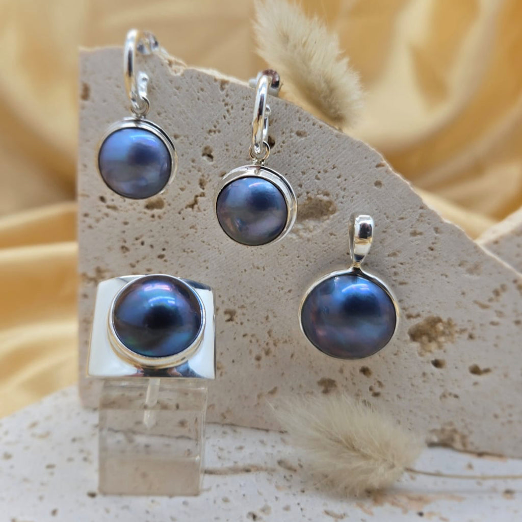 Set of pearl earrings on a display stand with a beige background