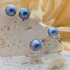Pair of blue pearl earrings on a stone stand with a soft yellow background