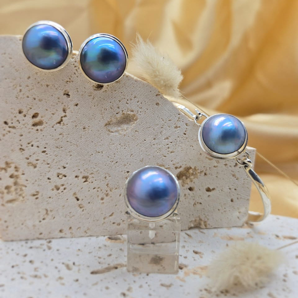 Pair of blue pearl earrings on a stone stand with a soft yellow background