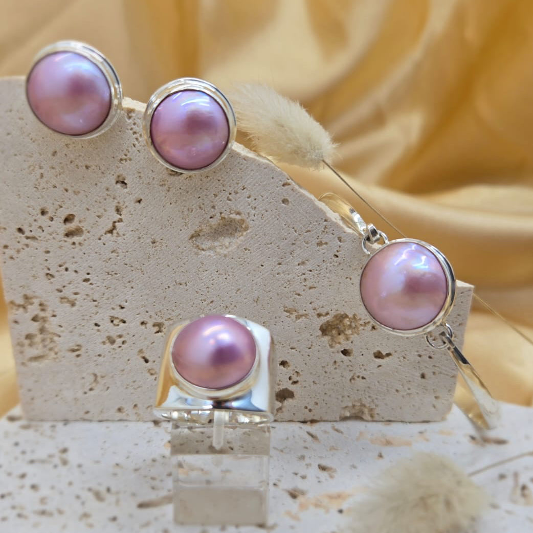 Pink pearl earrings on a stone stand with a soft yellow background