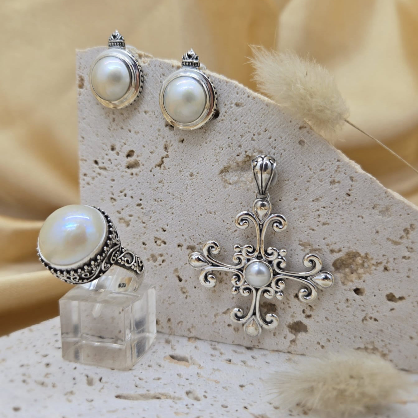 Silver jewelry set with pearls on a textured stone surface
