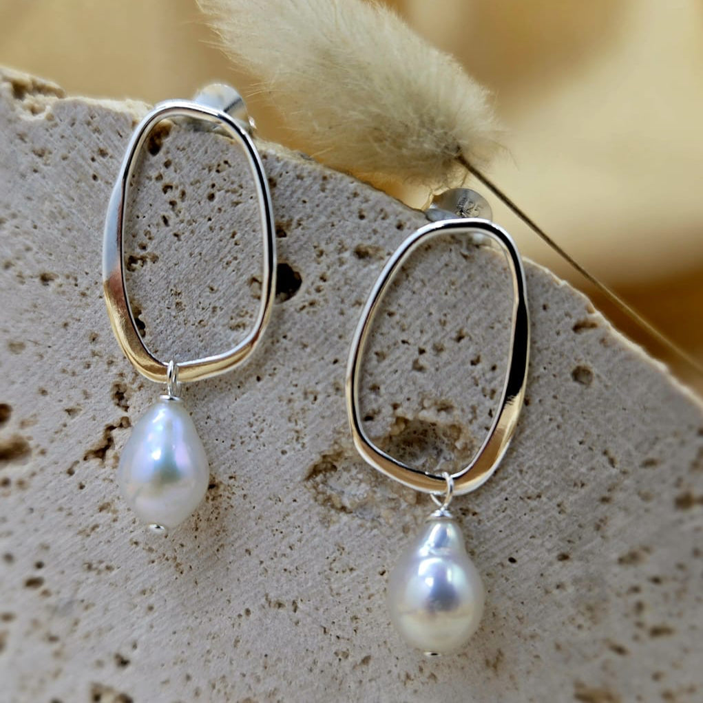 Silver earrings with pearls on a textured surface