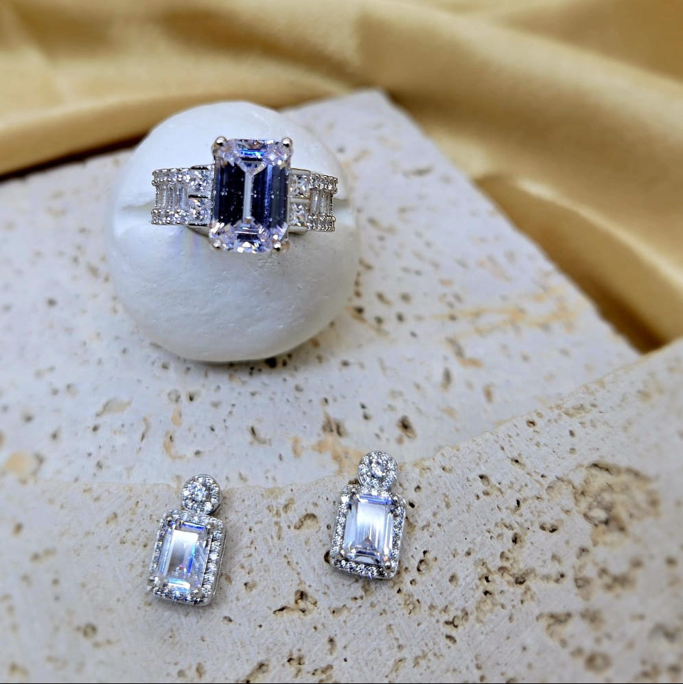 Silver ring and earrings with gemstones on a textured surface