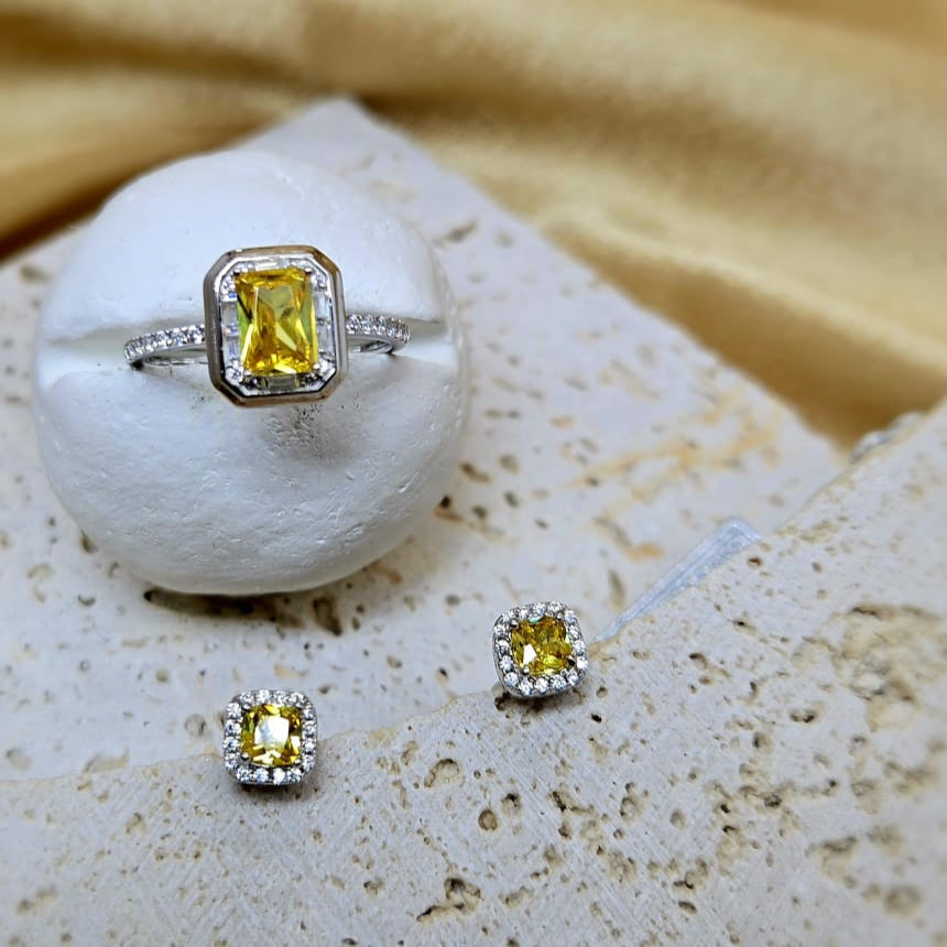 Silver ring with yellow gemstone on a white stone with a beige fabric background