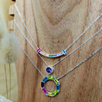Two necklaces with colorful gemstones on a wooden surface