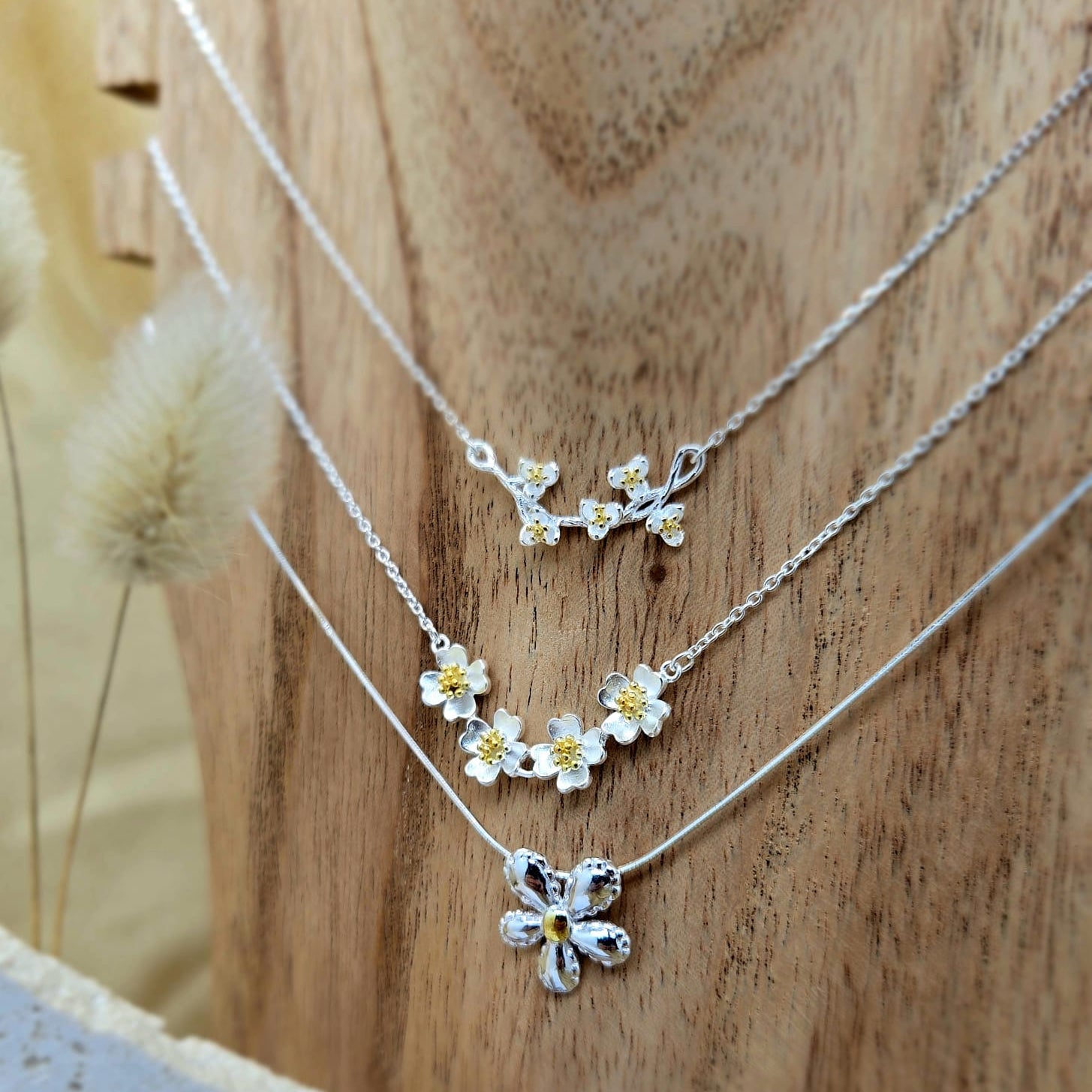 Silver flower necklaces on a wooden surface