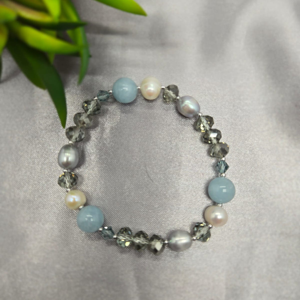 Beaded bracelet with blue, gray, and pearl beads on a light gray background