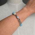 Bracelet with blue and pearl beads on a wrist against a neutral background