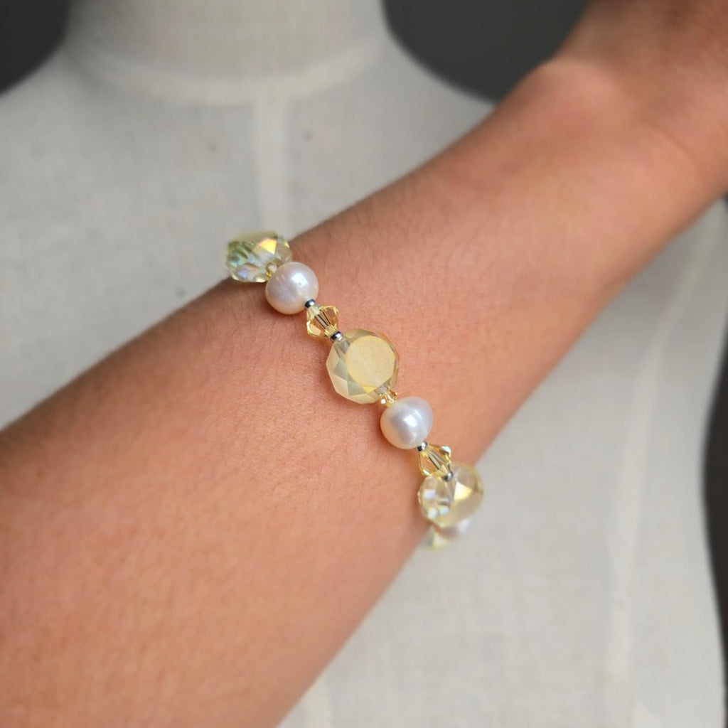 Bracelet with pearls and crystals on a wrist against a neutral background