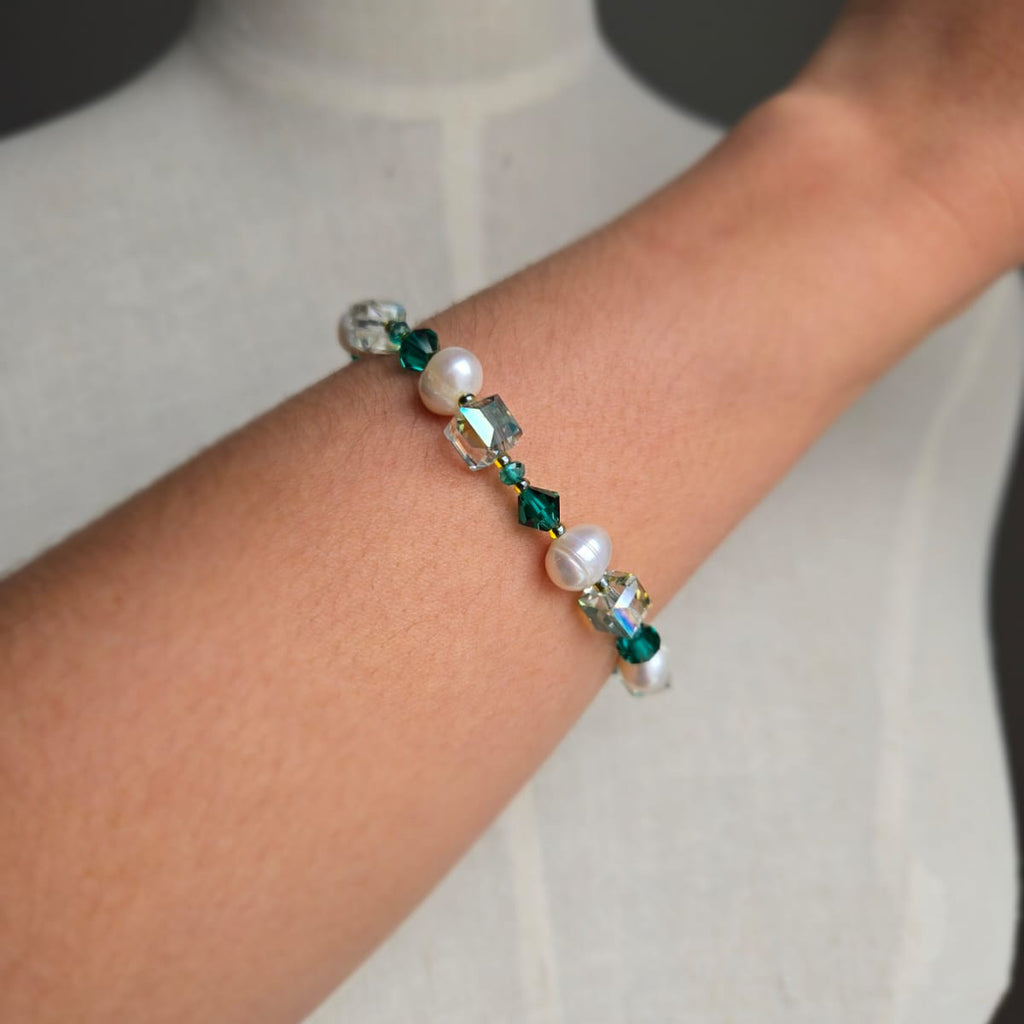 Beaded bracelet with green and clear beads on a wrist against a neutral background