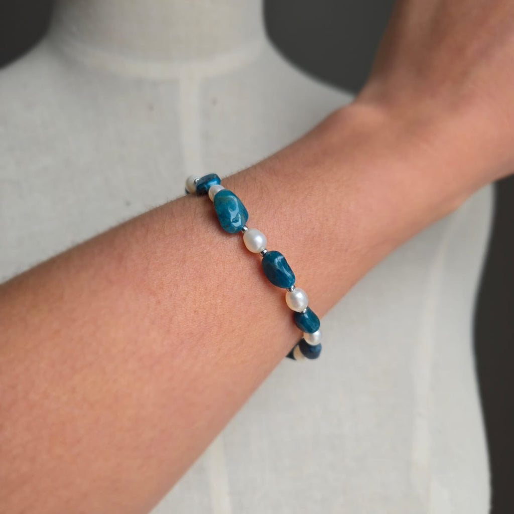 Beaded bracelet with blue and white beads on a wrist against a neutral background