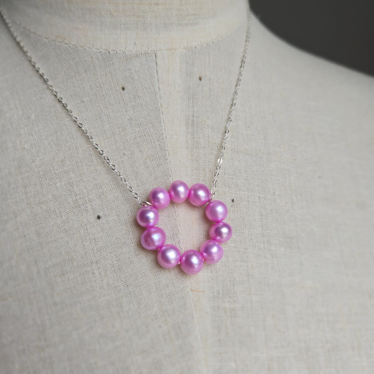 Necklace with a pink beaded pendant on a mannequin.