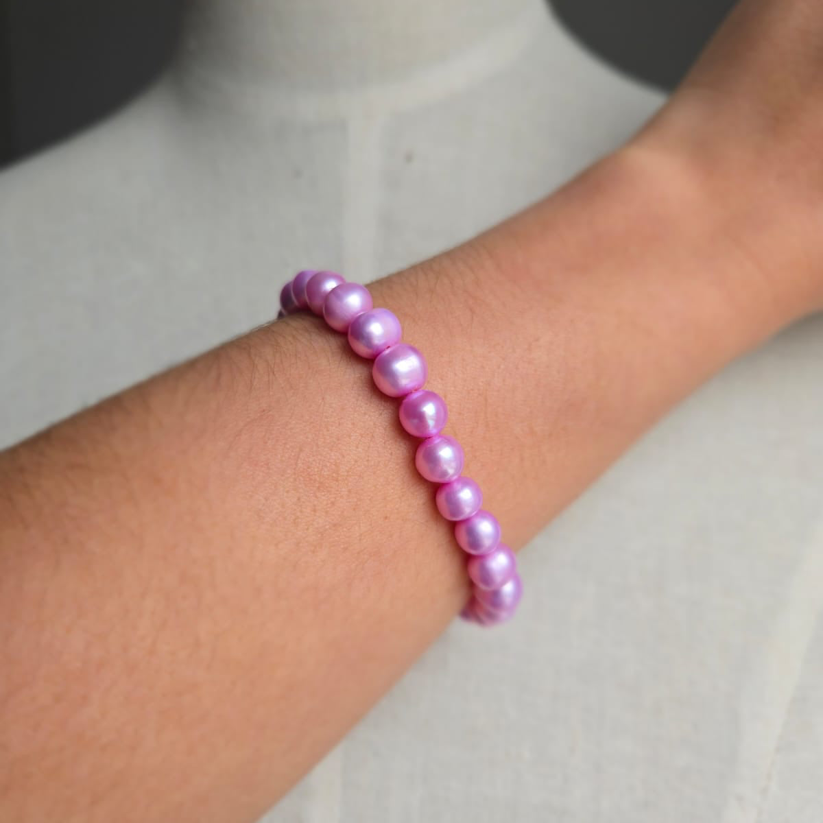 Pink beaded bracelet on a wrist with a neutral background