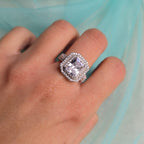 Silver ring with a large diamond on a hand against a light blue background