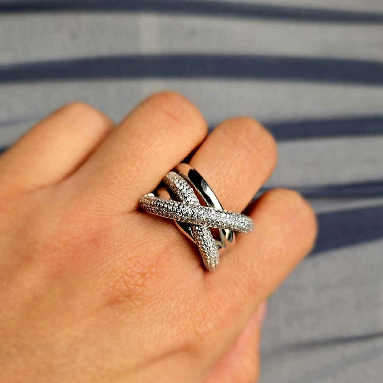Silver ring on a person's finger with a striped background