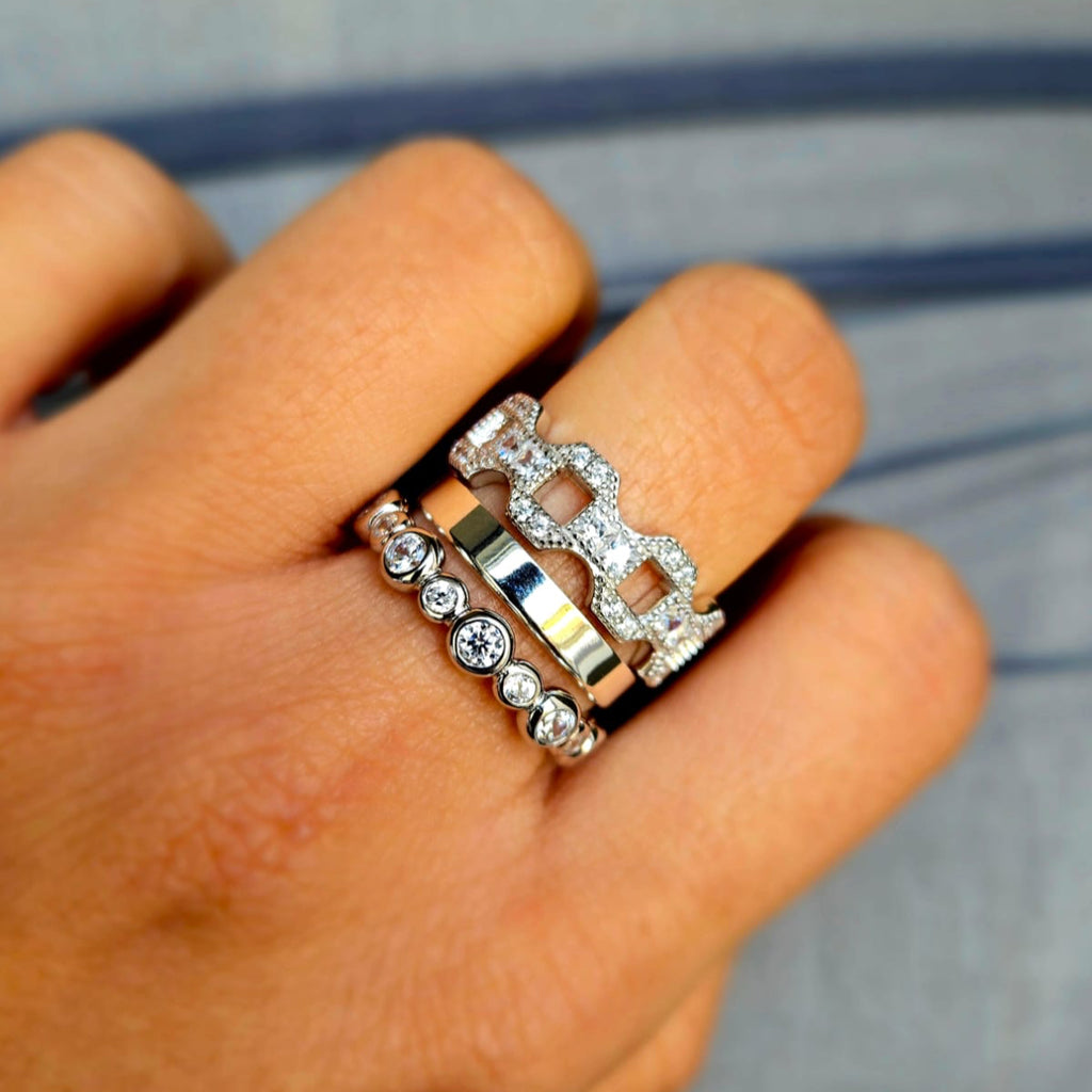 Hand wearing multiple silver rings with gemstones on a blurred background