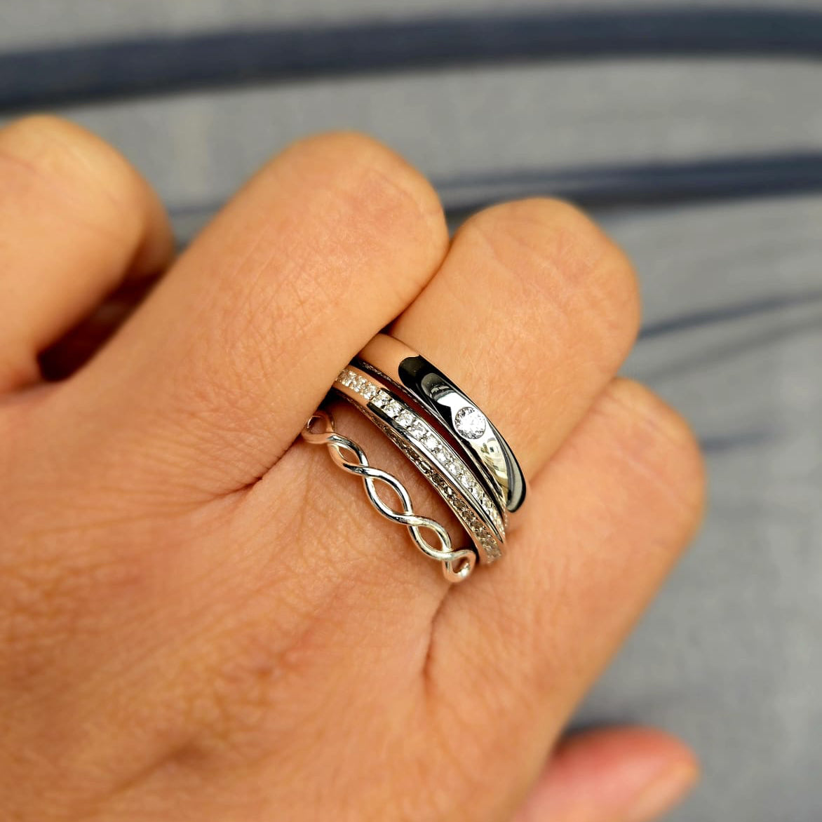 Hand wearing multiple rings with a blurred background