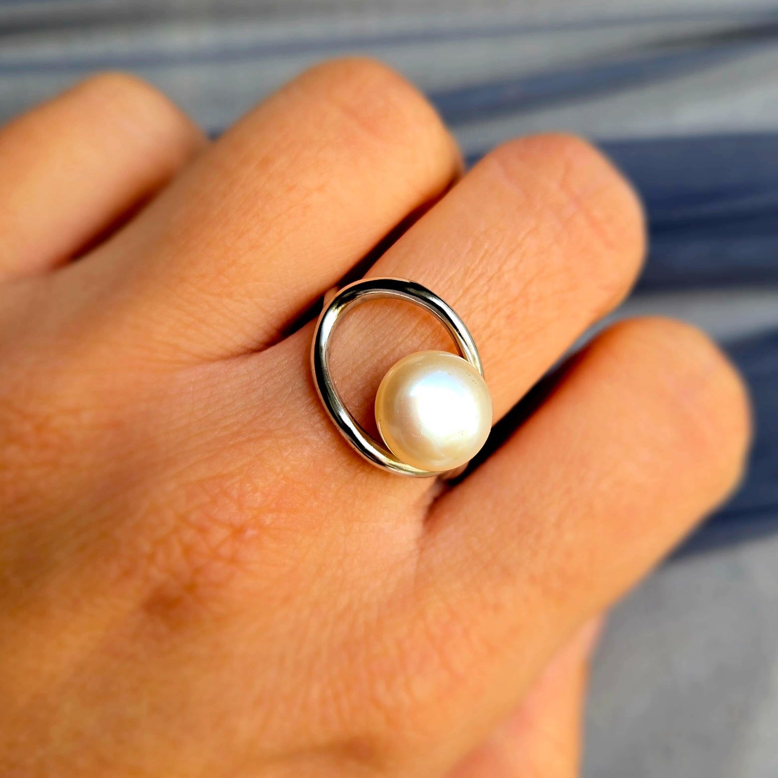 Pearl ring on a person's finger with a blurred background