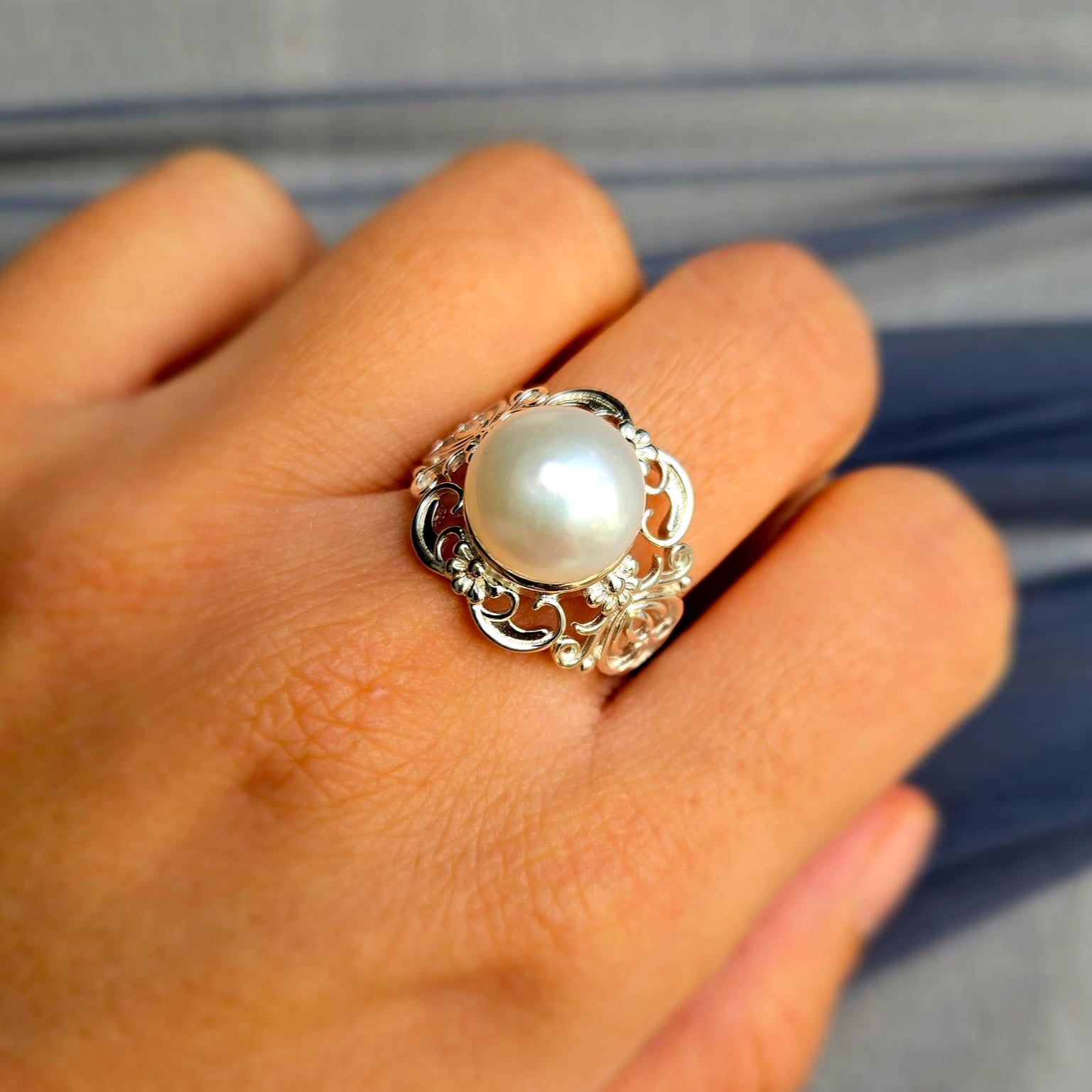 Pearl ring on a person's finger with a blurred background