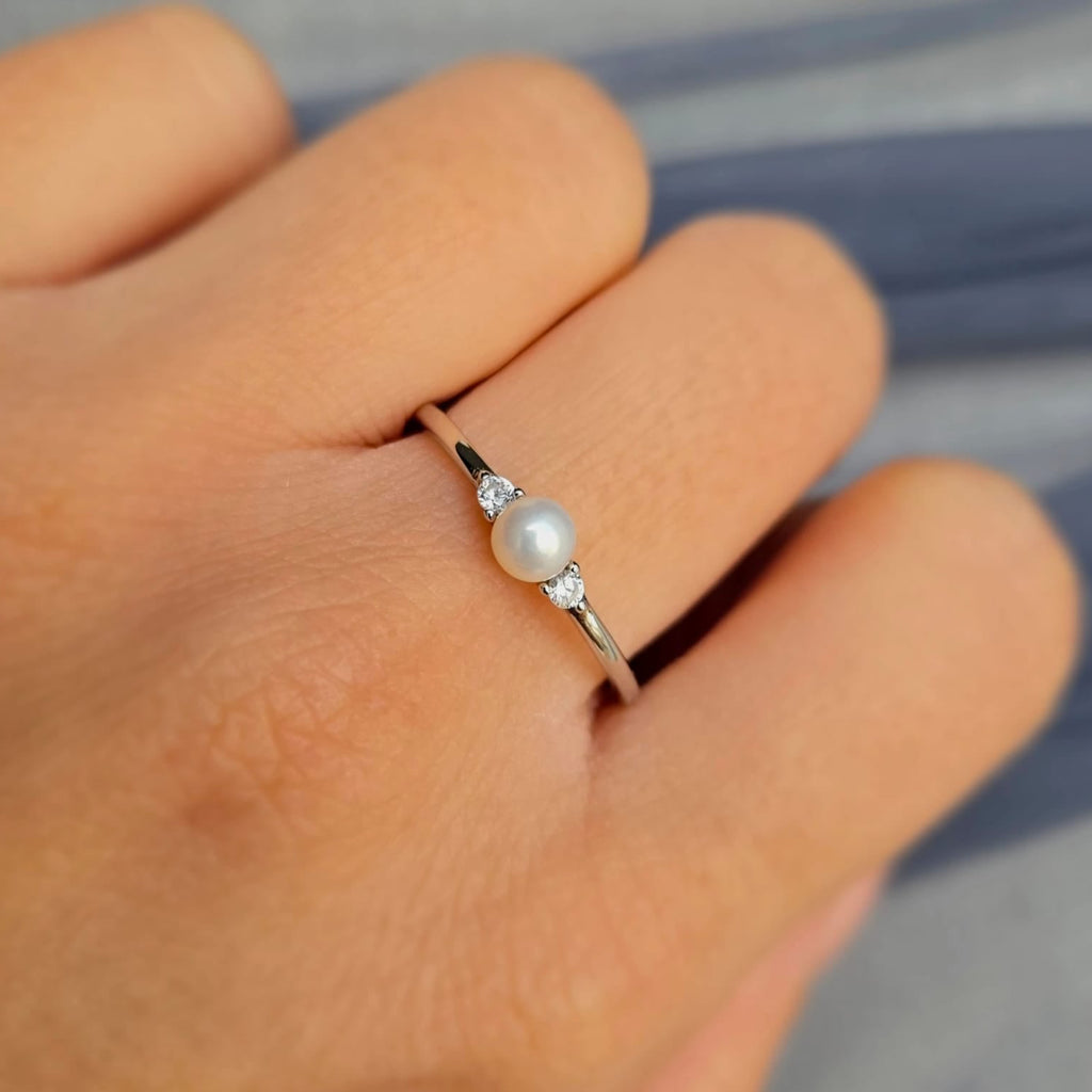 Pearl ring on a finger with a blurred background