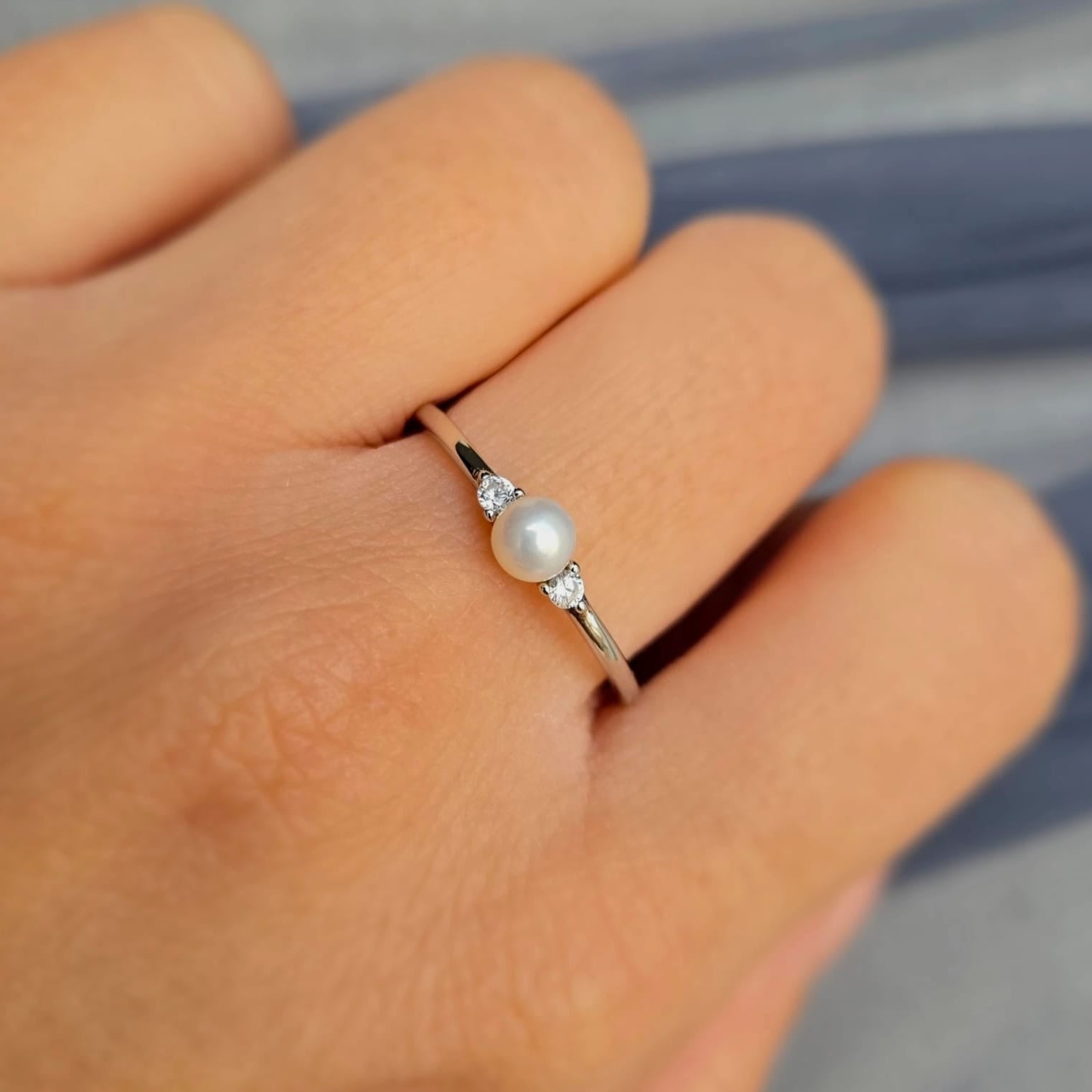 Pearl ring on a finger with a blurred background