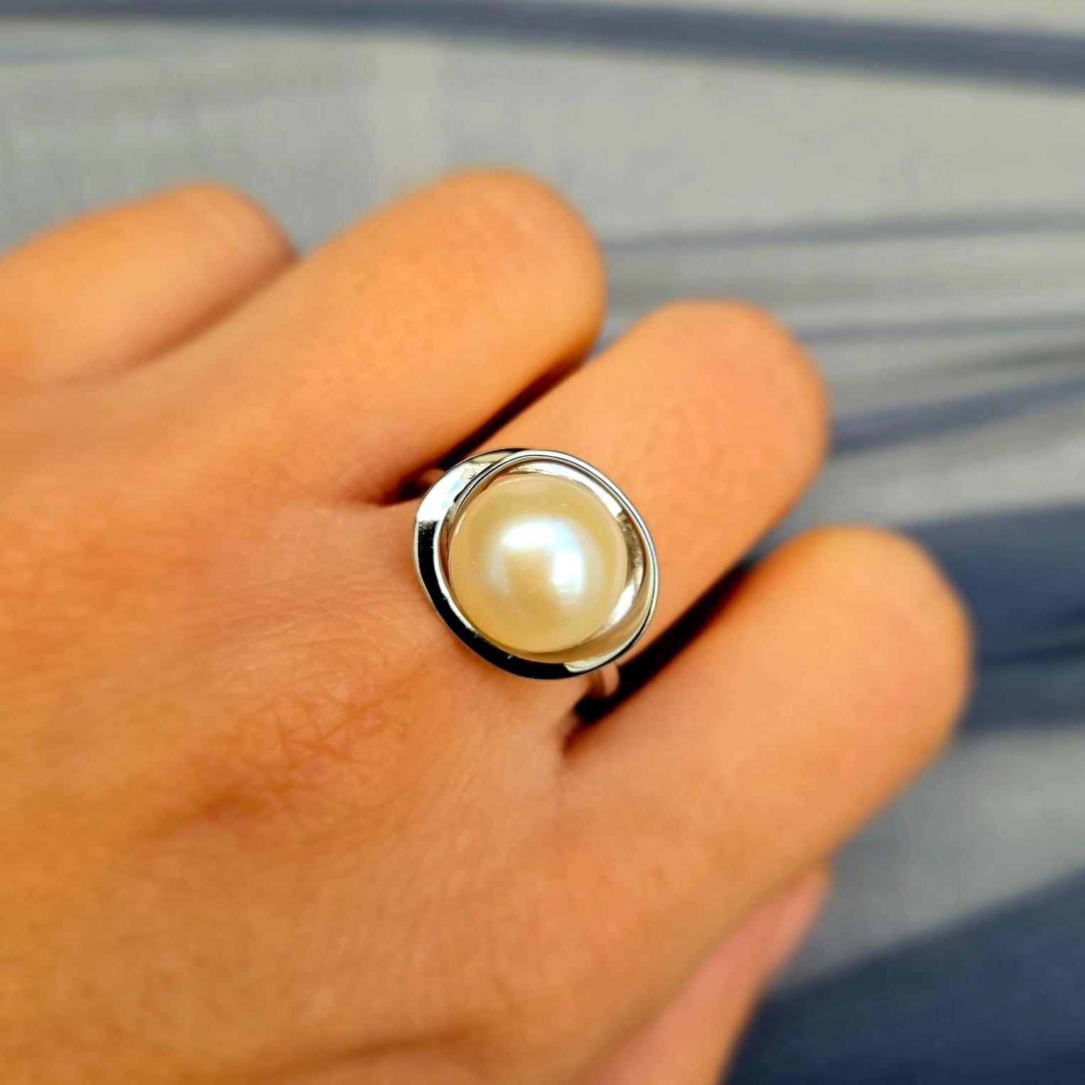 Pearl ring on a person's finger with a blurred background