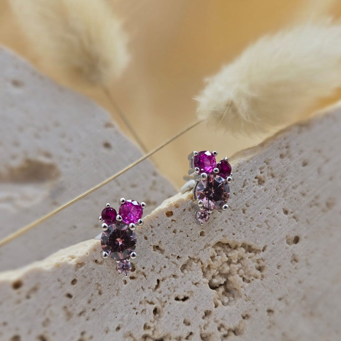 Pair of earrings with red gemstones on a textured beige surface