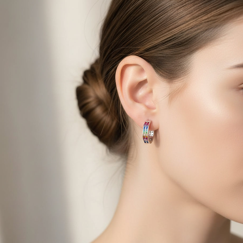 Silver hoop earring with colorful stones on a textured stone surface