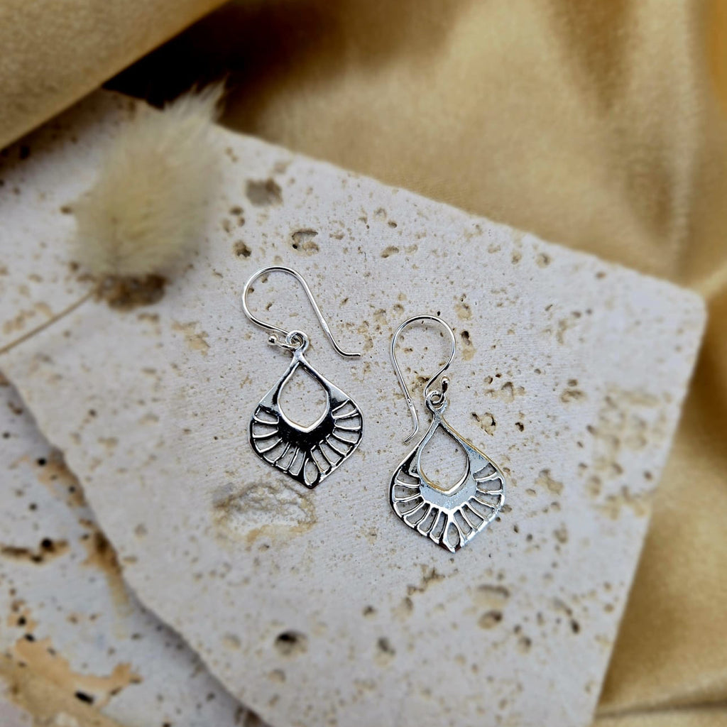 Silver earrings on a textured beige surface