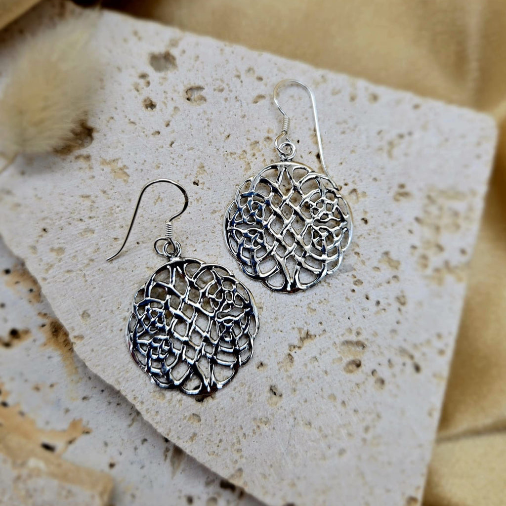 Silver earrings on a textured beige card