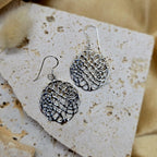 Silver earrings on a textured beige card