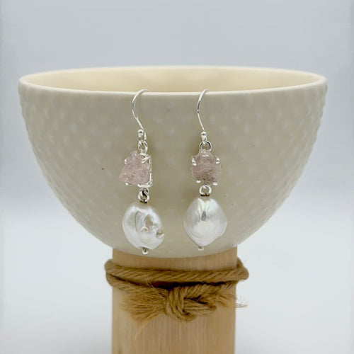 Pair of earrings with clear and pink gemstones displayed on a white bowl.