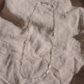 Silver chain necklace on a textured beige surface