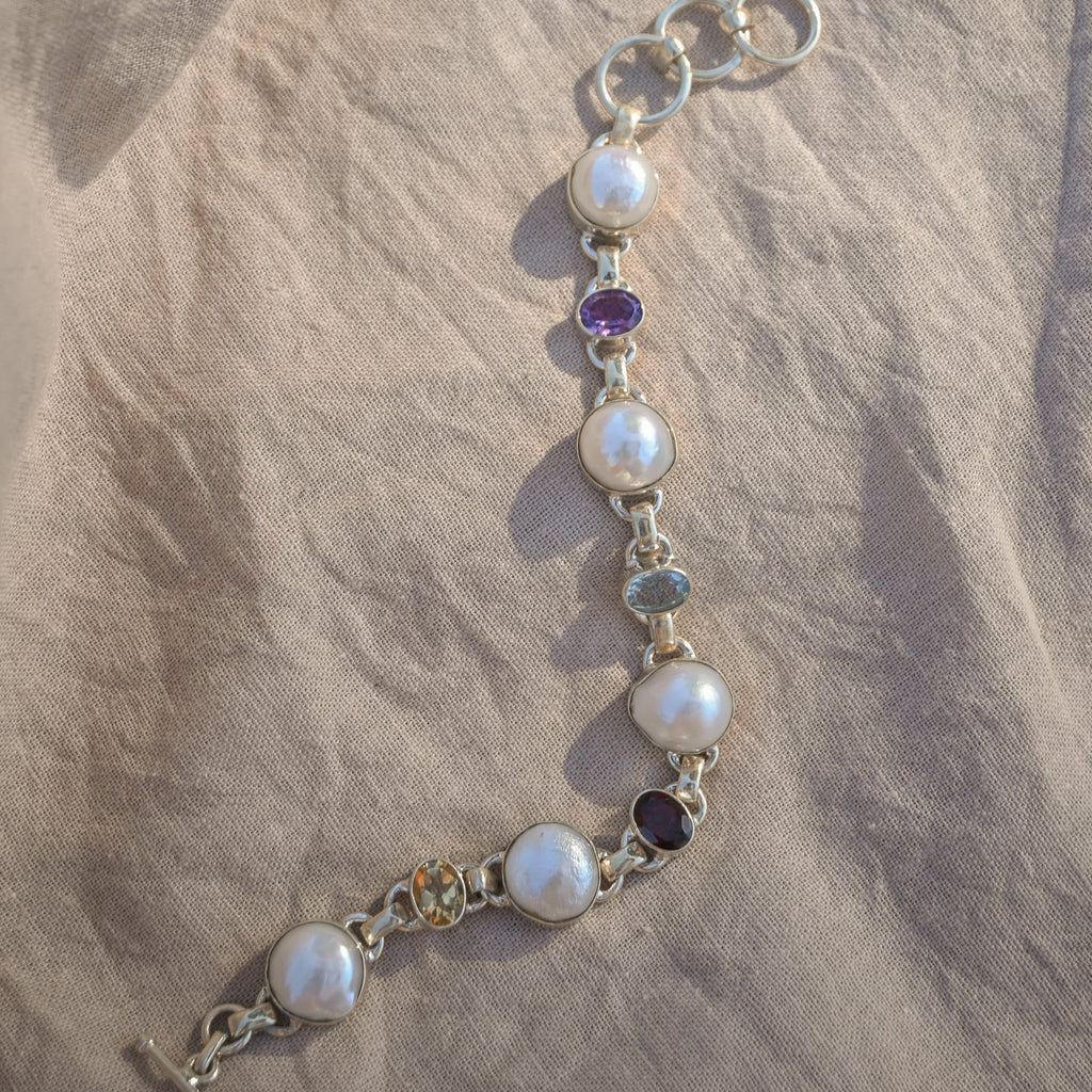 Pearl bracelet with gemstones on a beige fabric background