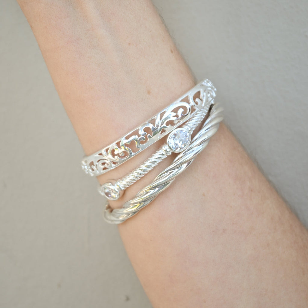 Silver bracelets on a wrist against a neutral background