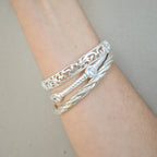 Silver bracelets on a wrist against a neutral background