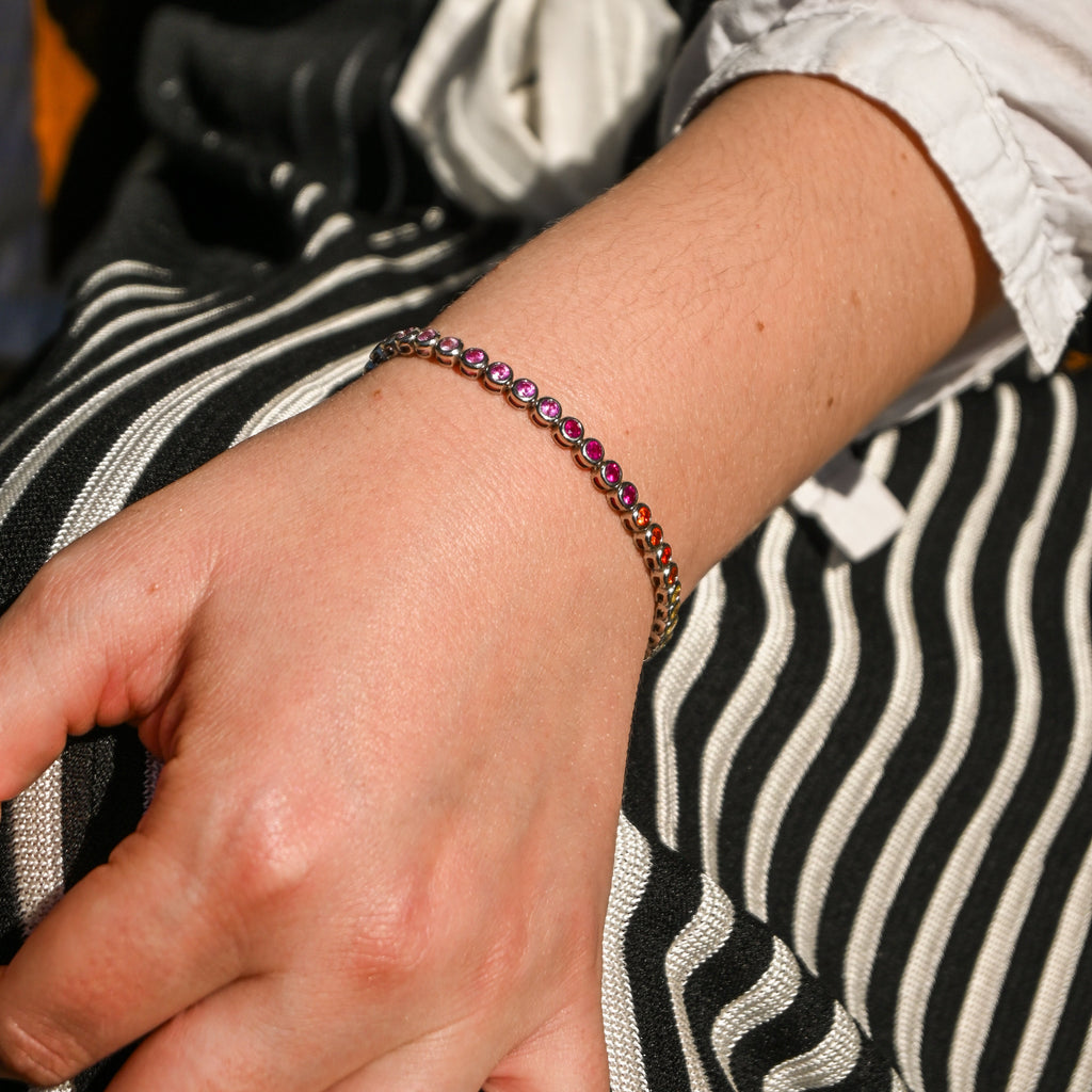 Close-up of a hand wearing a bracelet with a striped garment in the background