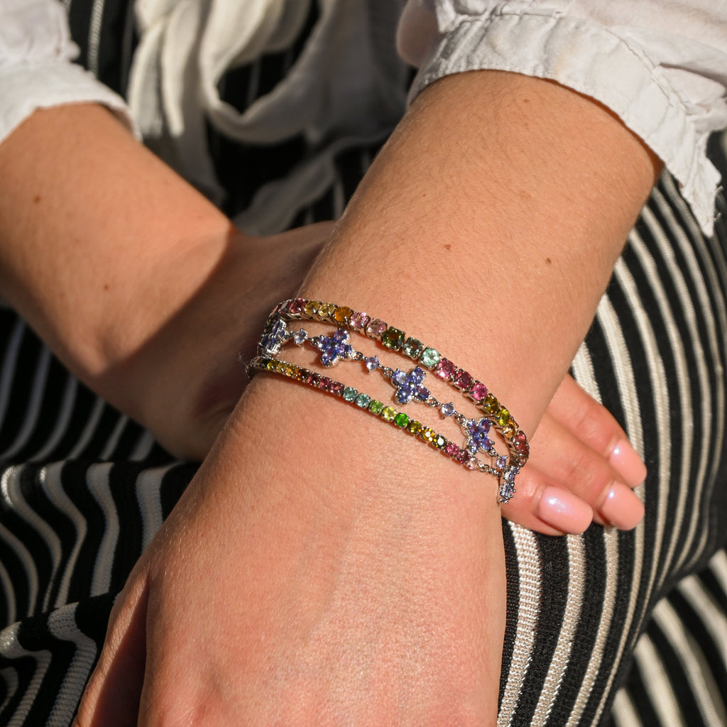 Close-up of a wrist wearing colorful beaded bracelets with a striped fabric background.