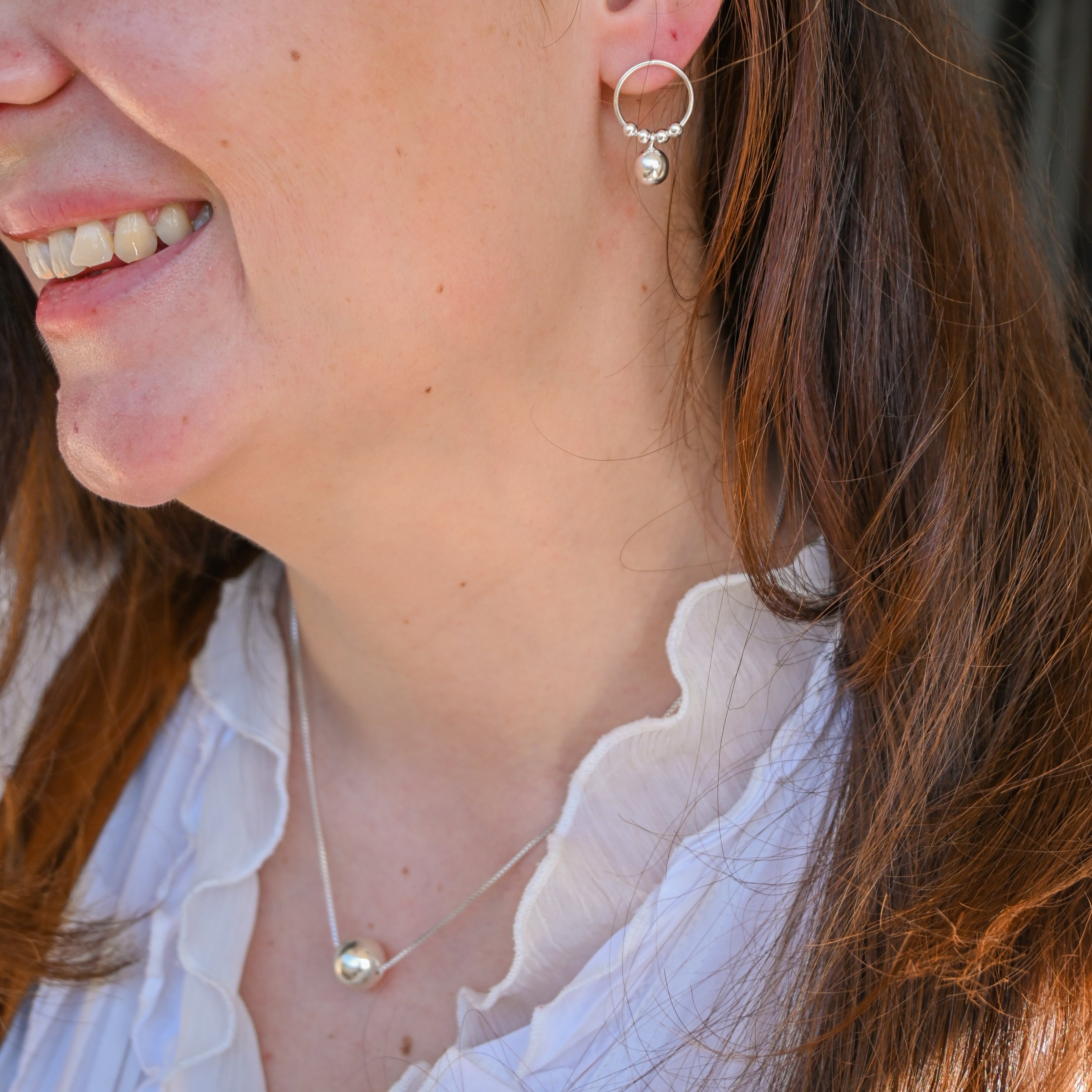 Close-up of a woman wearing hoop earrings and a necklace.