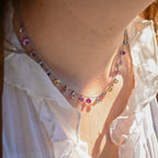 Close-up of a colorful beaded necklace worn by a person in a white shirt.