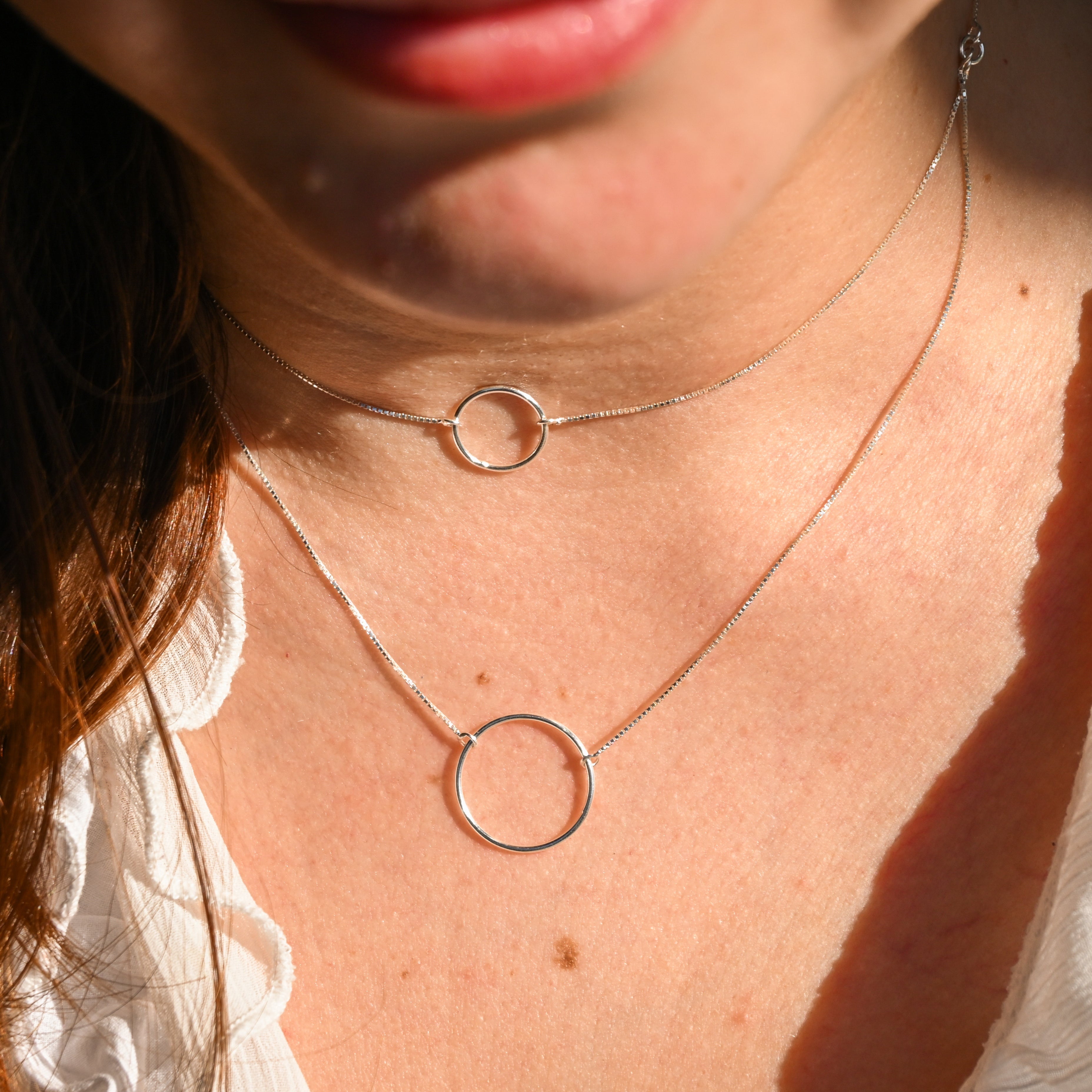 Close-up of a person wearing a silver necklace with circular pendants.